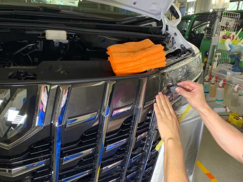 トヨタ アルファードのヘッドライトに、道具を使ってプロテクションフィルムを貼っているところ