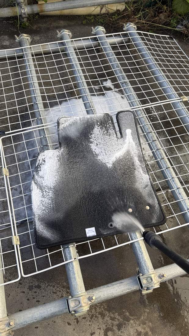 車から出したフロアマットを洗剤と水で丸洗いしているところ