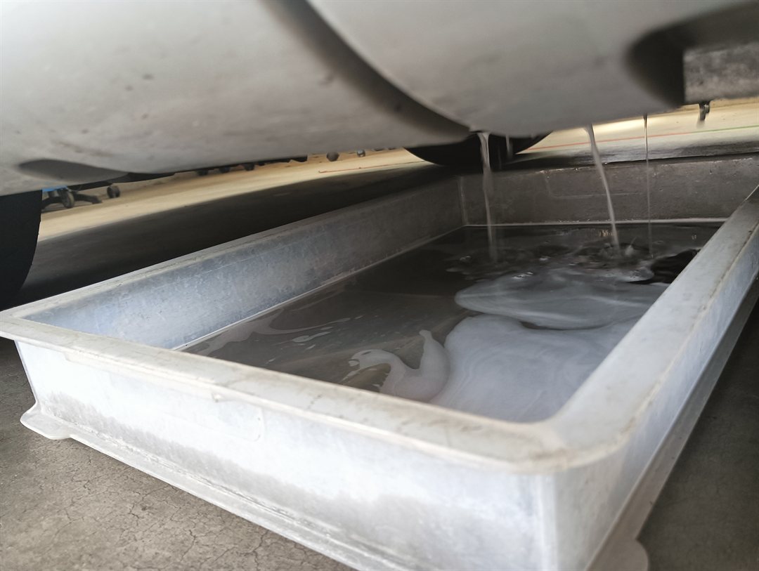エバポレーターを洗った水を、車の下で受けているところ