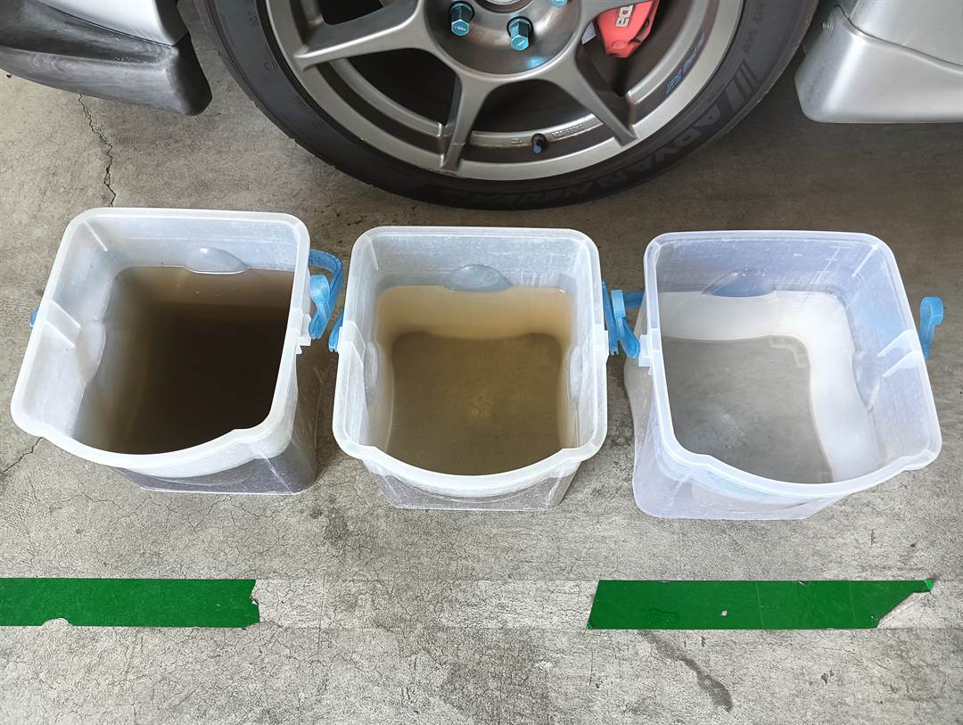 マツダ RX-7 のエバポレーターを洗った水。左はこげ茶色で、右にいくほど透明に近づいている